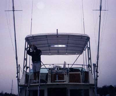 Atlantic Towers Top installed on a Hattaras 42 Convertible boat with a person standing near the helm.