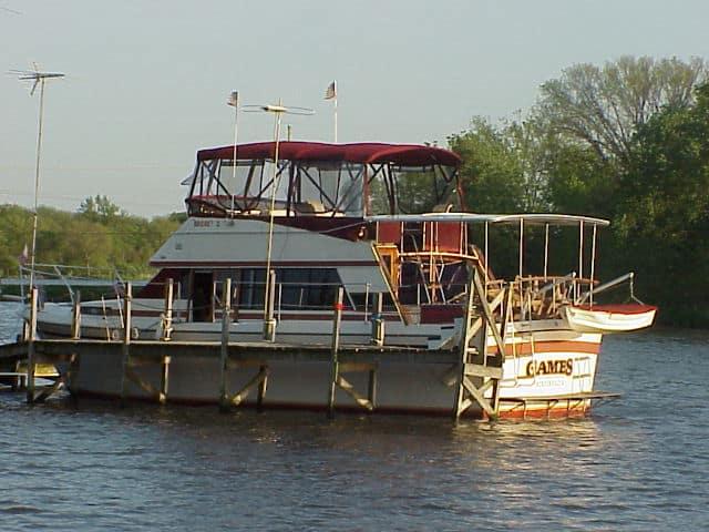 Bayliner Bodega boat with Atlantic Towers Aft Deck Top installed, docked by a wooden pier on calm water.