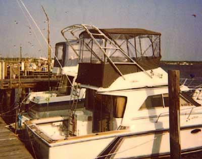 Atlantic Towers Arch installed on a Trojan 10.8 Meter Sedan boat at the marina, with a view of other boats and docks.
