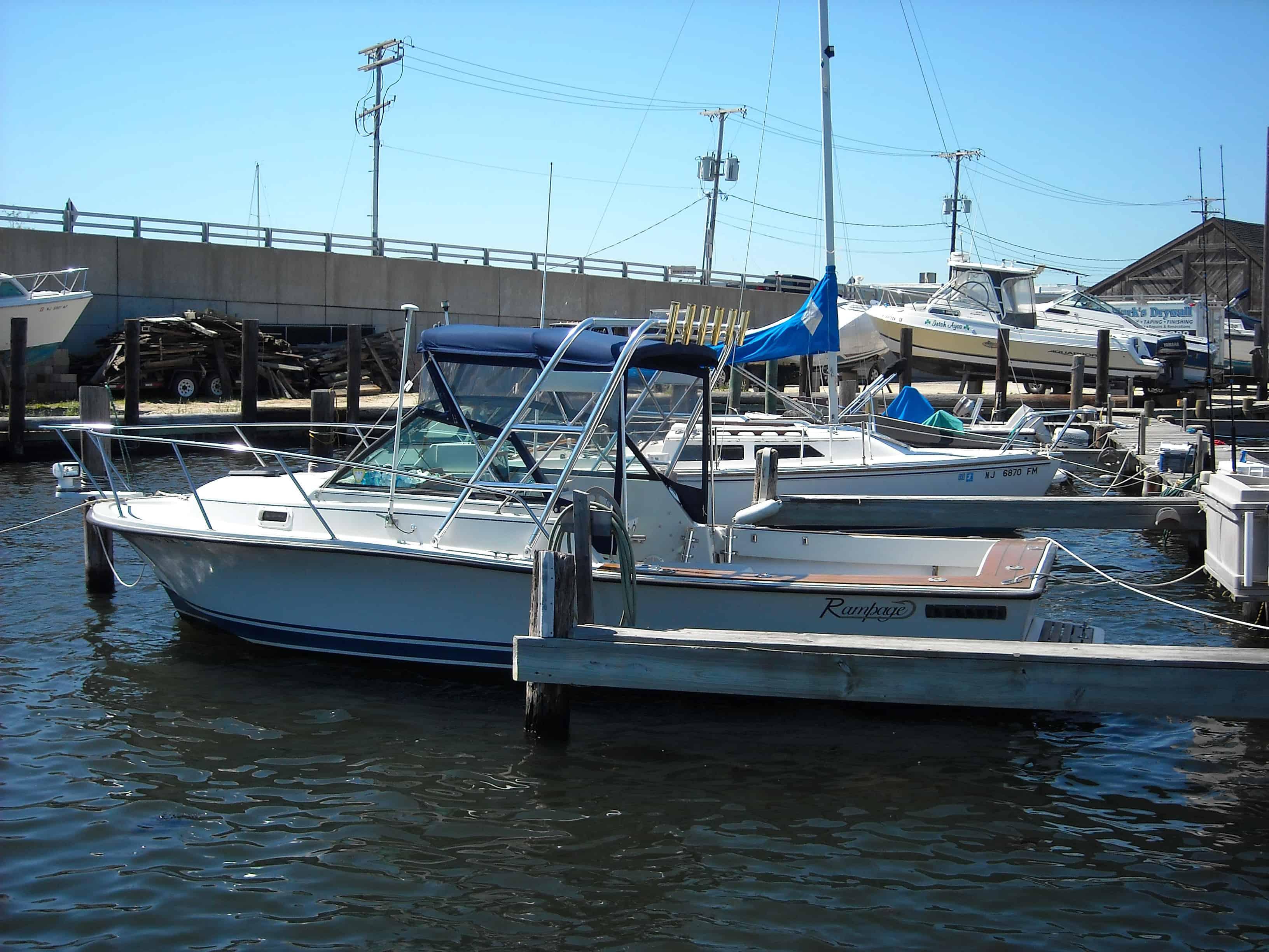 Rampage 24 Express boat docked with installed Atlantic Towers Arch and blue canvas canopy on a sunny day.