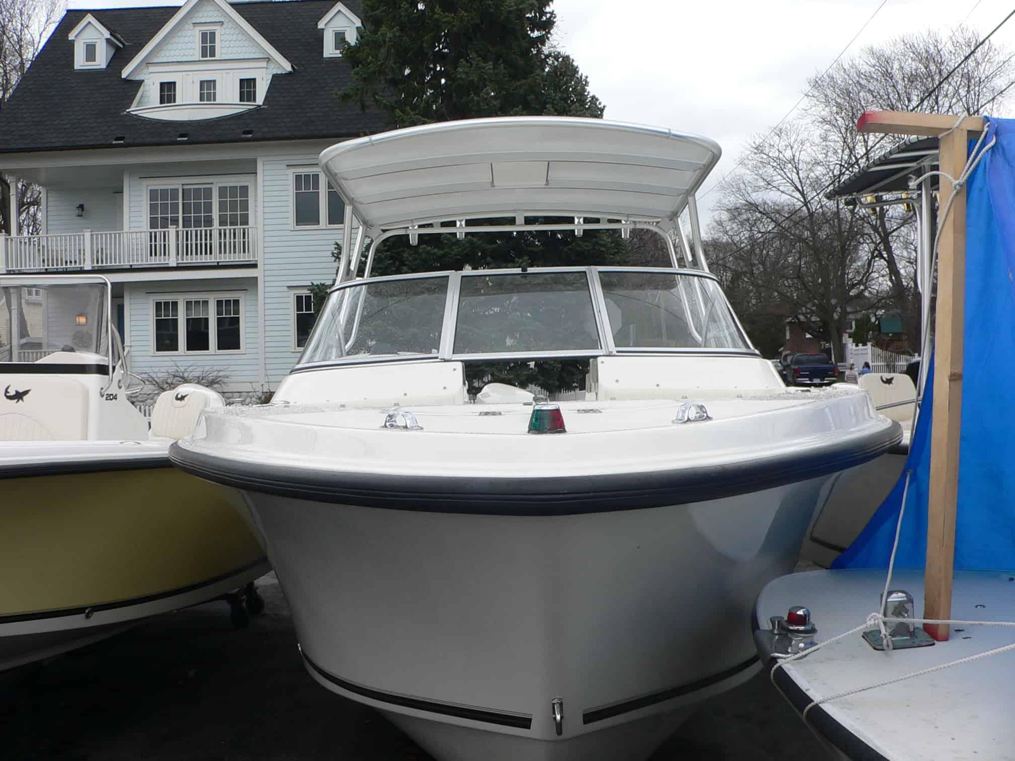 Front view of a Mako 216 Dual Console boat equipped with an Atlantic Towers Top canopy, docked among other boats.