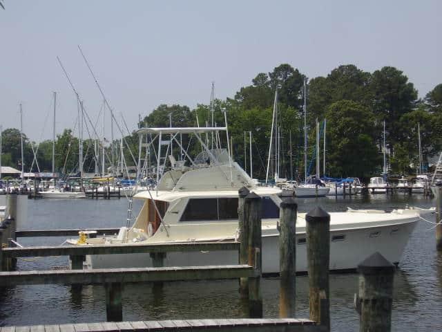 Hattaras 41 Convertible boat docked with an installed Atlantic Towers Top, surrounded by marina and trees.