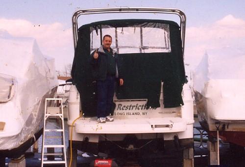 Man standing on the deck of a Four Winns 258 Vista boat equipped with an Atlantic Towers arch at a marina.
