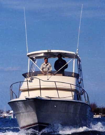 Atlantic Towers Top installed on a Tiara 3300 Flybridge, with two individuals at the helm on a sunny day.