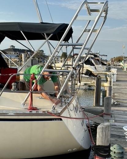 A person cleans an Atlantic Towers Arch on a boat docked in a marina surrounded by other boats.