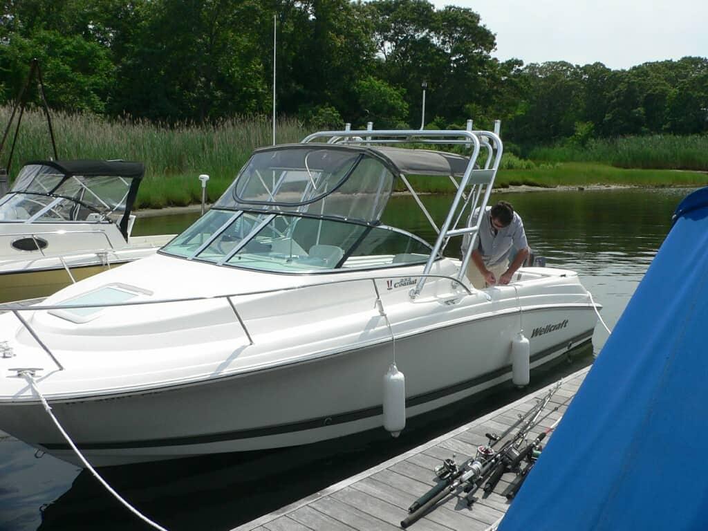 Wellcraft 232 Coastal boat docked with a person aboard and an installed Atlantic Towers arch above the cockpit.