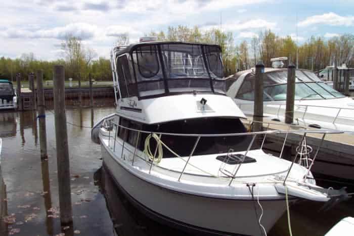 Carver Mariner boat docked with Atlantic Towers arch installed, featuring black canvas enclosure on upper deck.