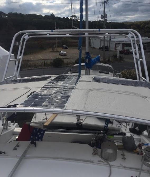 Atlantic Towers Arch installed on a Simpson Catamaran with solar panels on the deck and a flag at the stern.