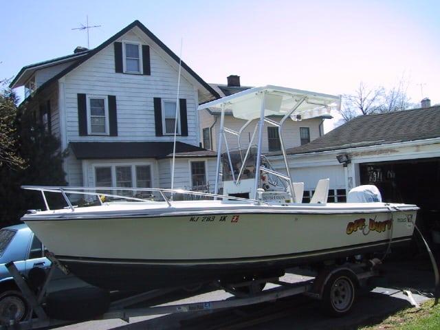 Wellcraft Fisherman boat with Atlantic Towers T-Top on trailer parked near a house on a driveway.