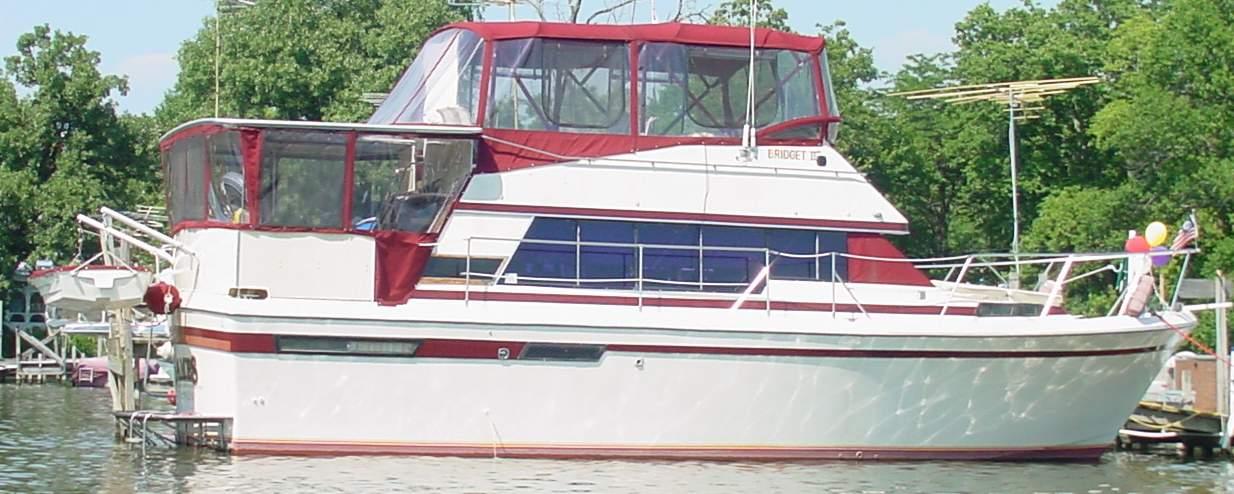 Bayliner 4050 Bodega boat with Atlantic Towers Cockpit Sun Shade installed, docked on calm water near trees.
