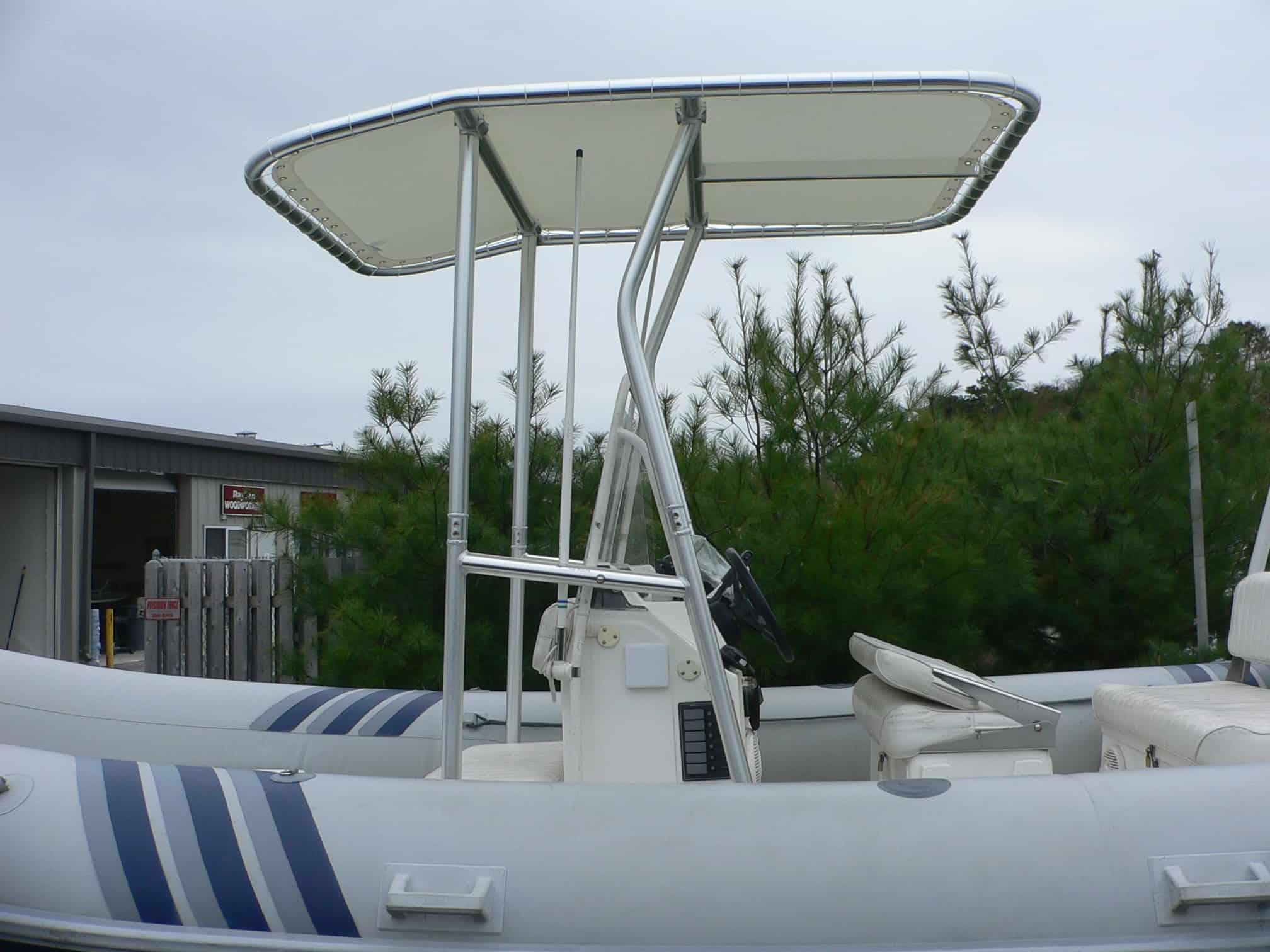 Atlantic Towers T-Top installed on an AB Inflatables 5.70VS boat, with a backdrop of greenery and a storage building.