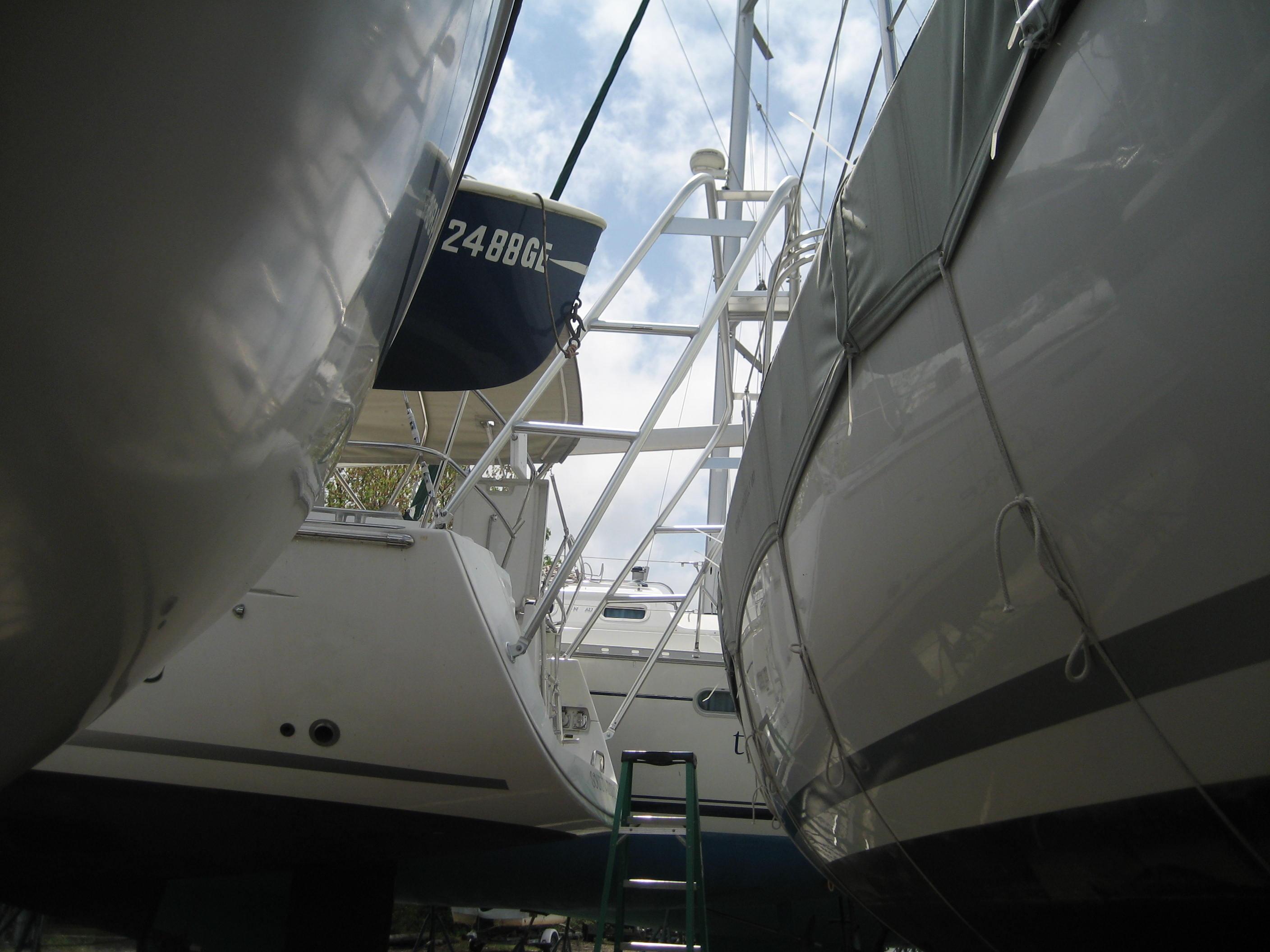 Atlantic Towers Arch installed on a Beneteau boat between two other boats in a marina with a green ladder below.