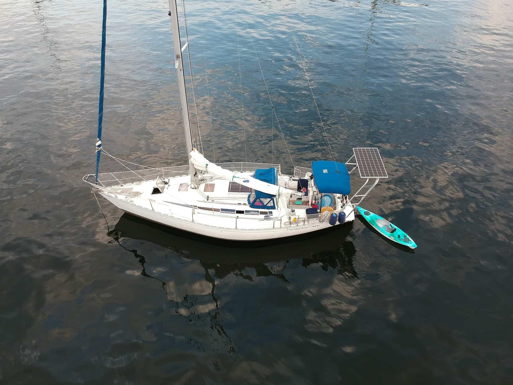 A sailboat with an Atlantic Towers Arch and a kayak in calm waters, showcasing its setup and accessories.
