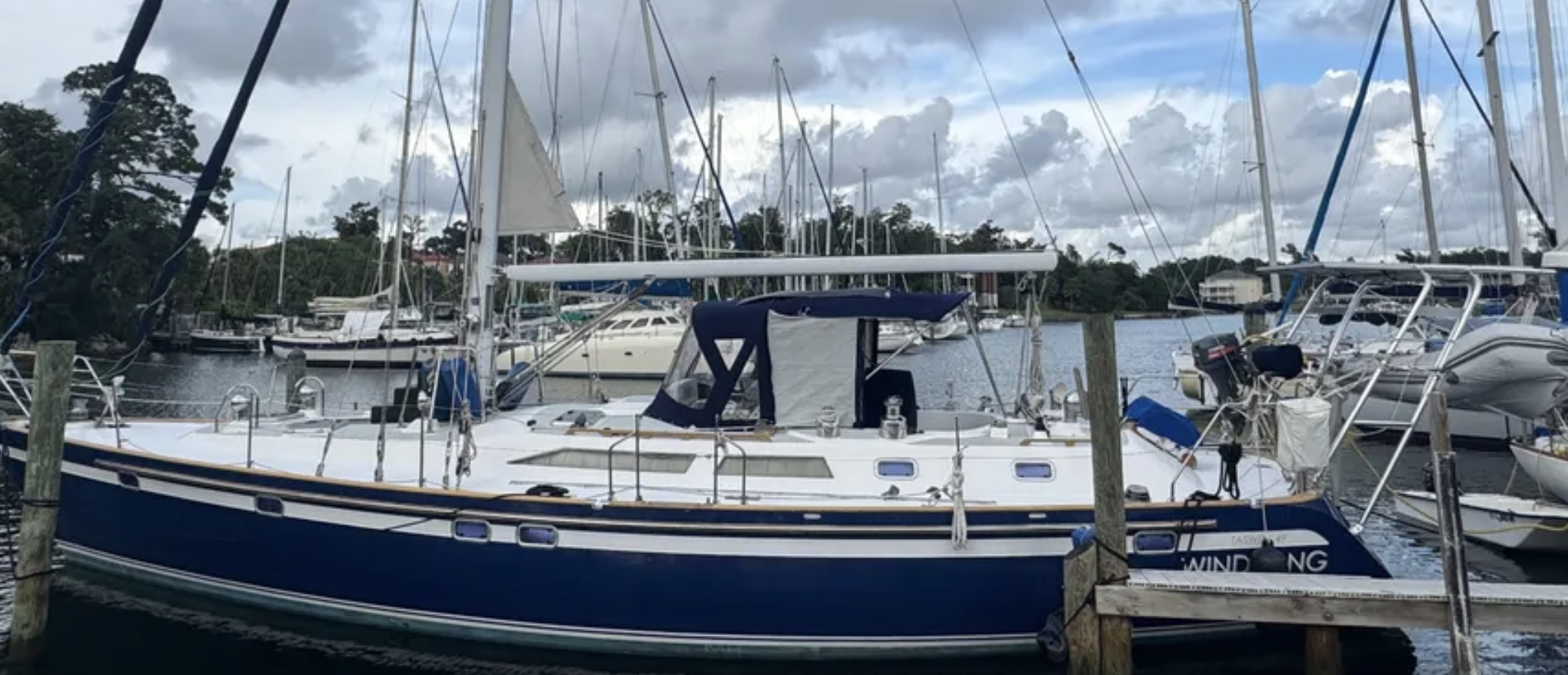 Sailboat docked at marina equipped with Atlantic Towers Arch behind the cockpit and navy blue canvas covers over cabin.