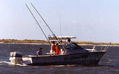Atlantic Towers Top installed on Rampage 24 Express boat with three people fishing on calm water near shoreline.