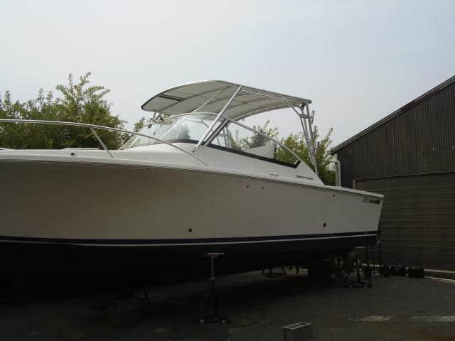 Luhrs 28 Open boat with installed Atlantic Towers Top arch, parked on stands near a building and trees.