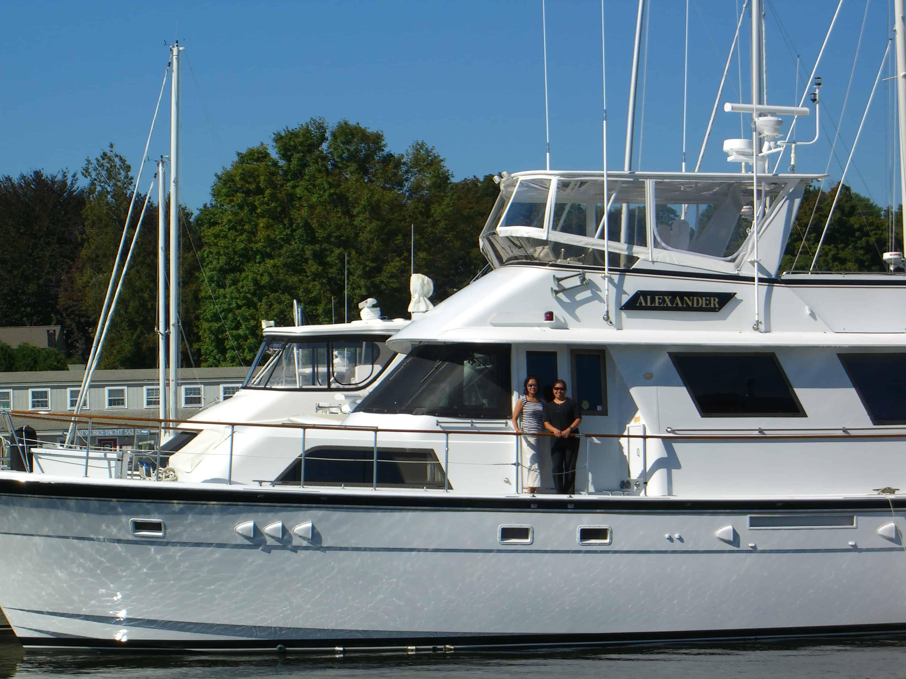 Two people standing on the deck of a Hattaras 61 Motor Yacht equipped with Atlantic Towers Top enclosure.