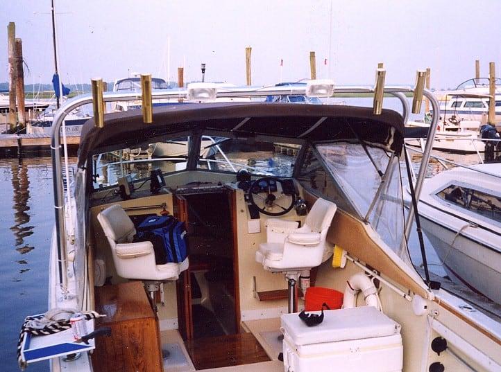 Interior view of a boat cockpit with a helm, two captain chairs, storage cooler, and Atlantic Towers arch installed above.