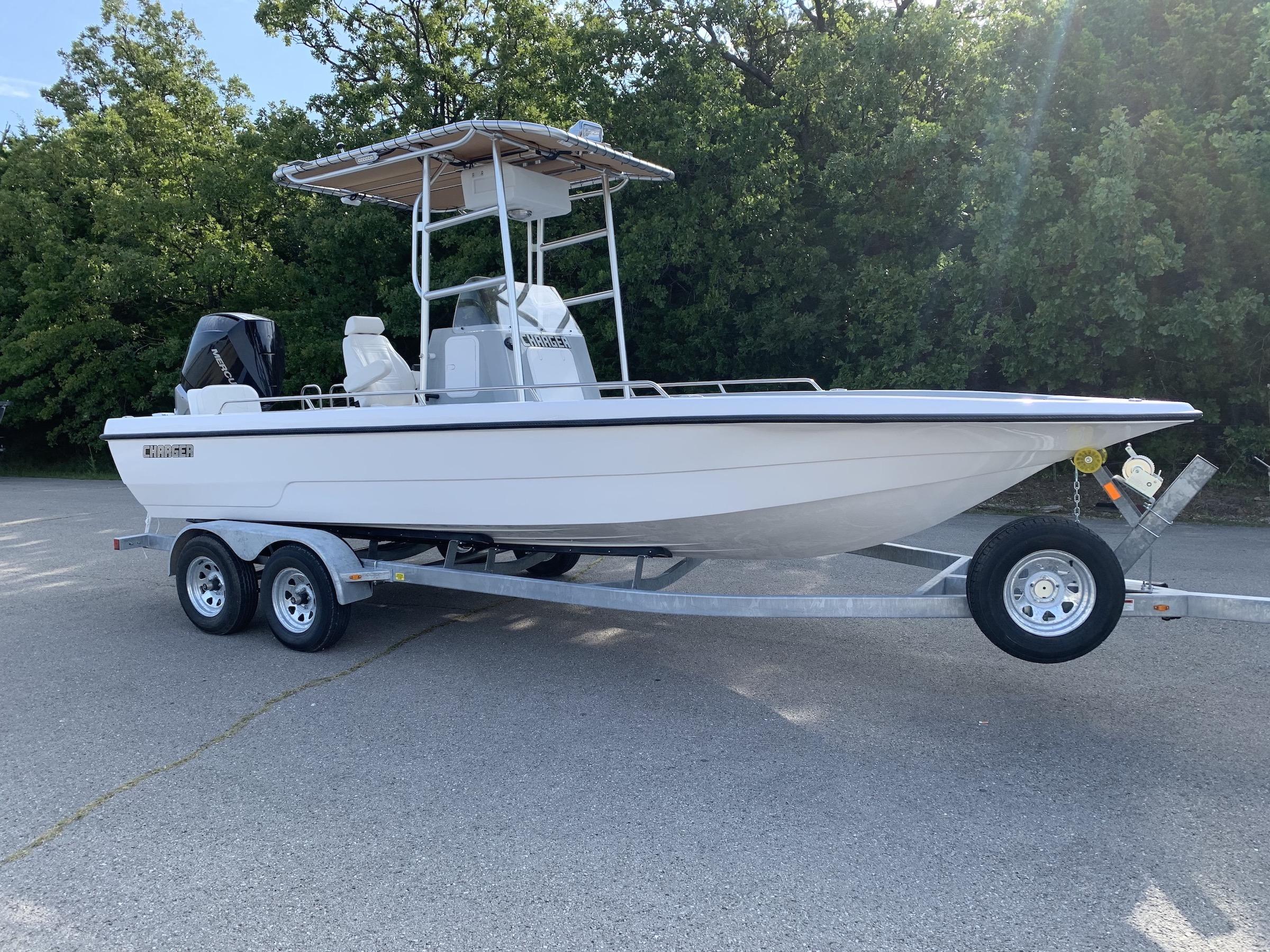 White Charger boat with Atlantic Towers T-Top installed, mounted on a dual-axle trailer outdoors near trees.