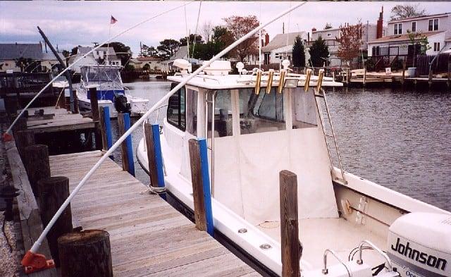 Atlantic Towers Accessories mounted on a white boat docked beside a wooden pier in a residential waterfront area.