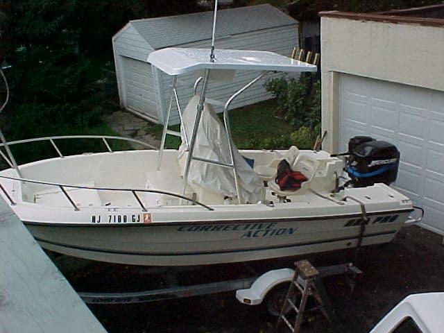 Sea Pro 170 Center Console boat with Atlantic Towers T-Top installed, parked on a trailer near garages.