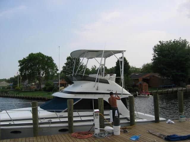 Alt text: Atlantic Towers Top installed on a Trojan 11 Meter Sedan boat at a dock, with a person working on it.