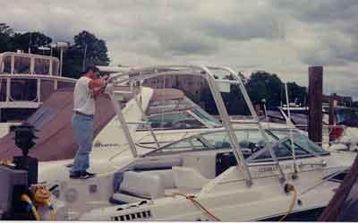 A person installing an Atlantic Towers Arch on a Regal 265/270/276 Commodore boat at a marina.