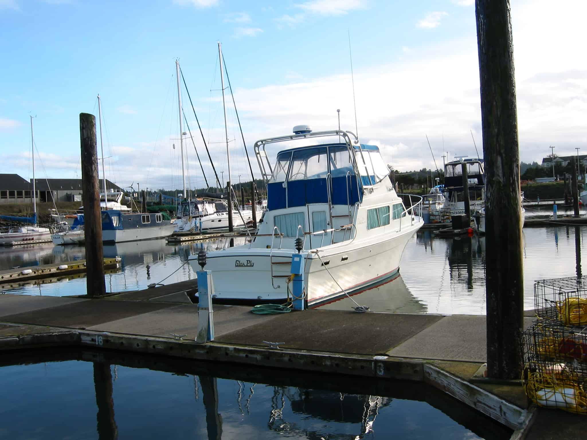 Glass Ply 28 boat docked in marina with Atlantic Towers Arch installed above the cabin roof under a partly cloudy sky.