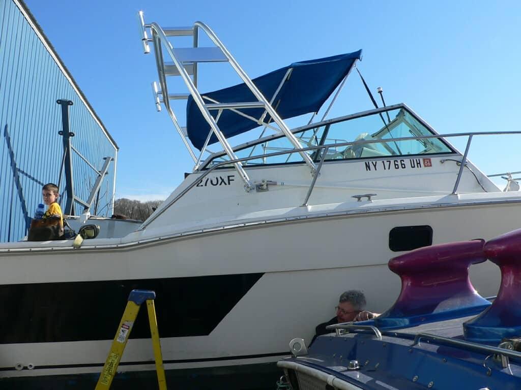 Aquasport 270 Express boat with installed Atlantic Towers Arch and blue canopy beside dock and workers.