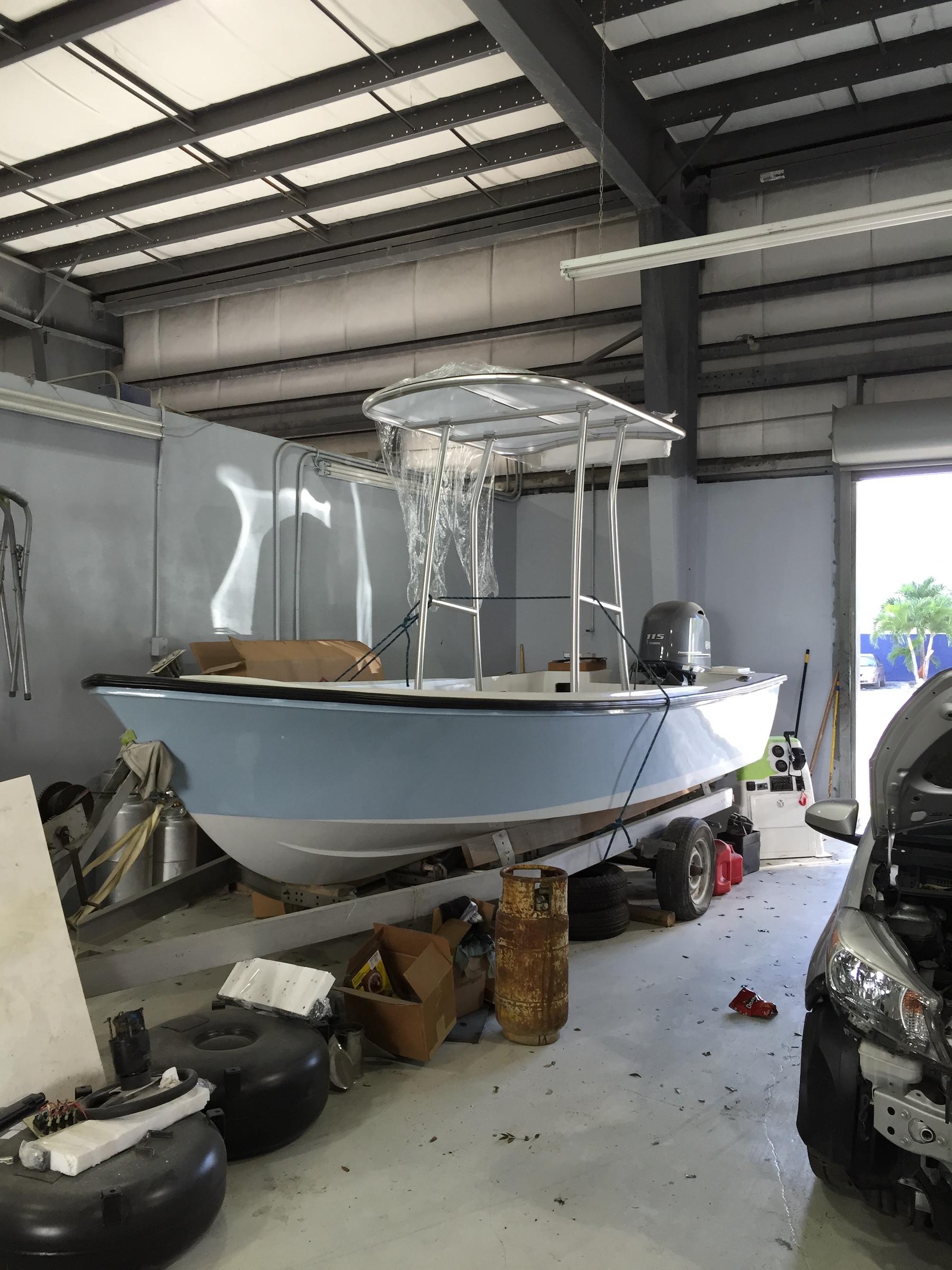 Aquasport boat with installed Atlantic Towers T-Top inside a workshop, surrounded by tools and a partially visible car.