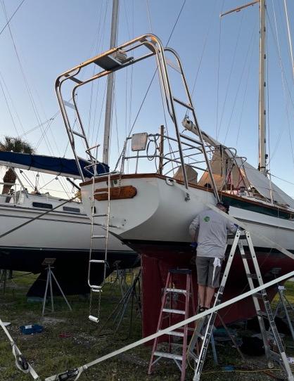 Atlantic Towers Arch installed on the stern of a Cabo Rico sailboat with a person on a ladder performing maintenance.