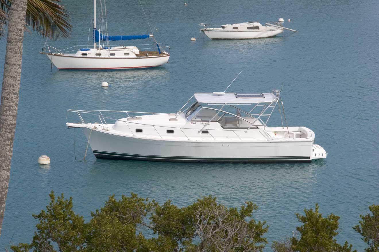 Atlantic Towers Top installed on a Mainship 34 Pilot boat, moored in a tranquil blue bay with other boats nearby.