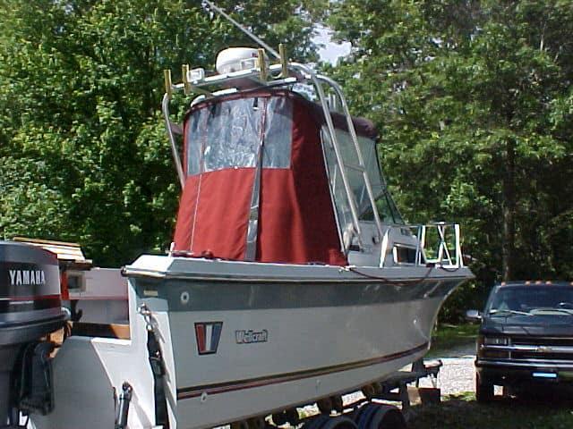 Wellcraft 230 Sportsman boat showing the rear with a red canvas cover and Atlantic Towers Arch installed on a trailer outdoors