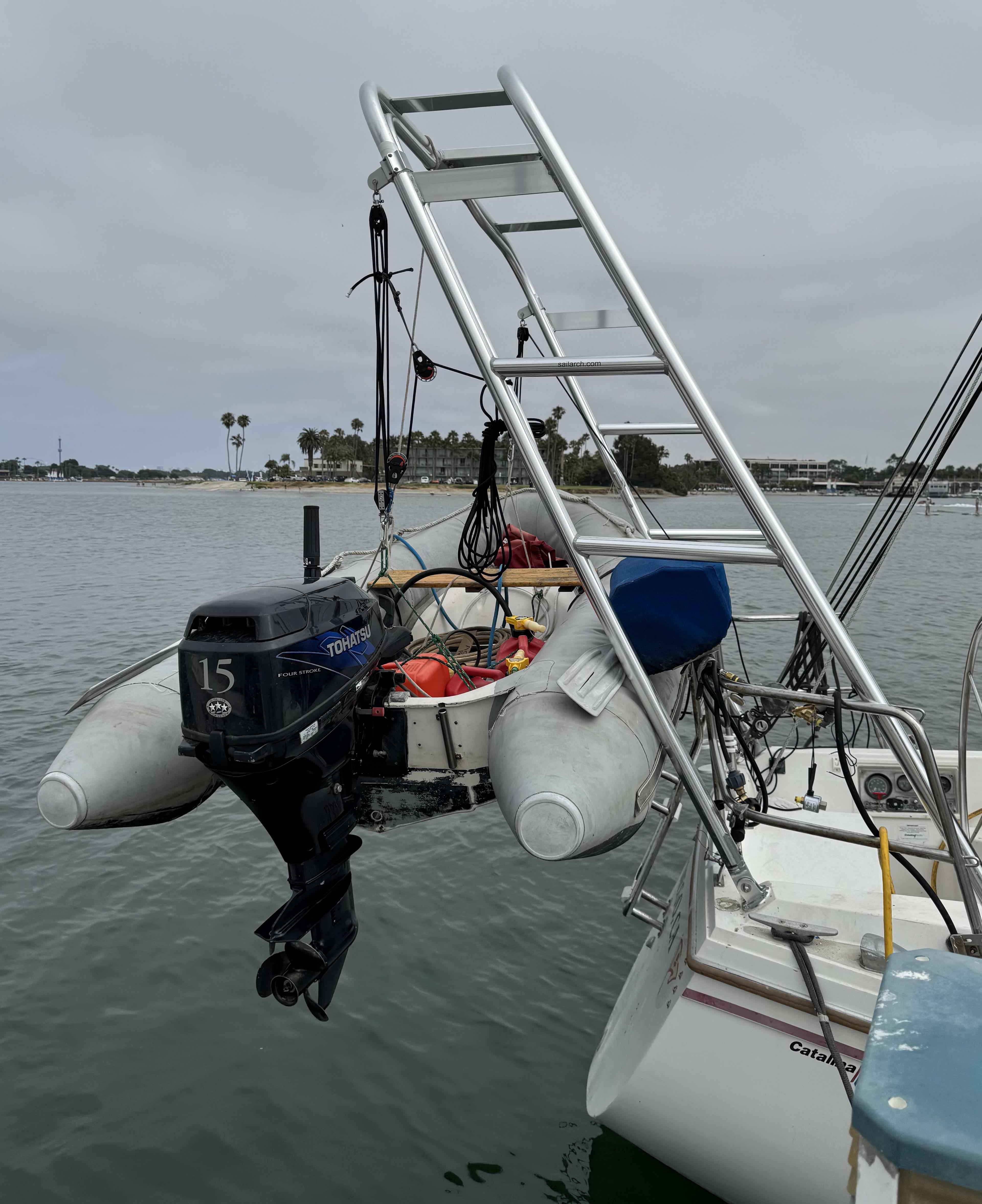 Inflatable dinghy with motor hanging from a Catalina sailboat using an installed Atlantic Towers Arch on a calm overcast day.