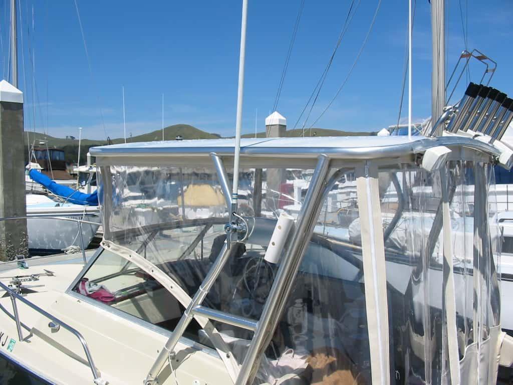 Skipjack boat equipped with Atlantic Towers Top featuring metal frame and clear protective enclosure in a marina.