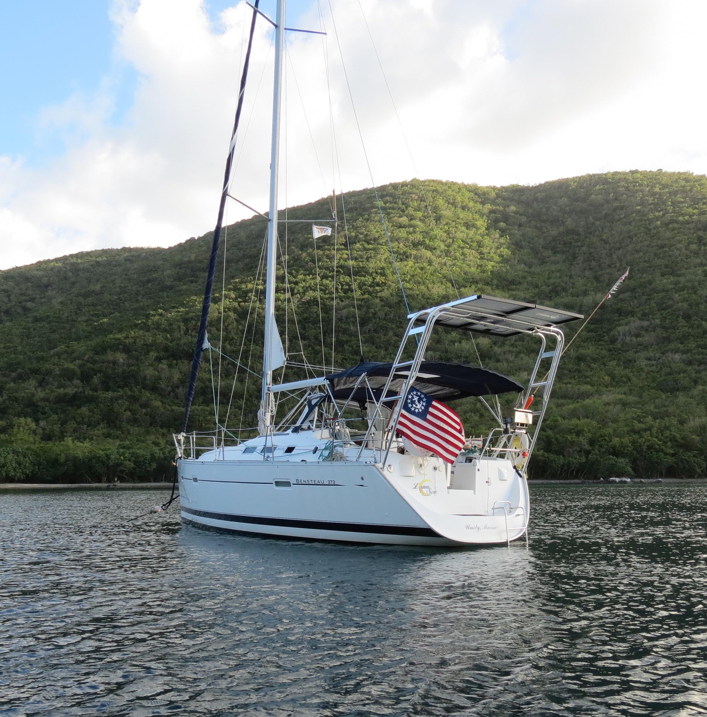 Atlantic Towers Arch installed on a Beneteau sailboat anchored in a serene bay with hills in the background.