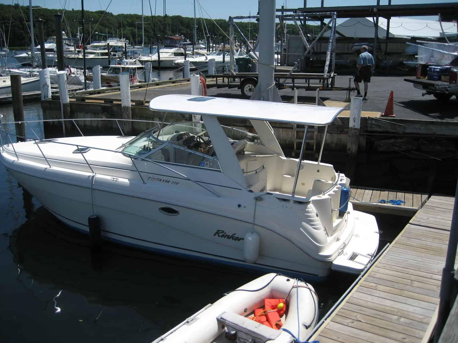 Rinker 310/312 Fiesta Vee boat docked with an installed Atlantic Towers Top arch under a marina structure.