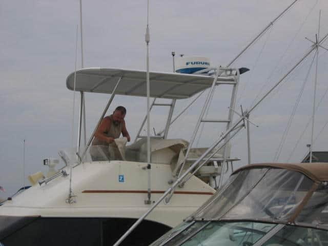 Man working on Ocean 32 SuperSport boat with installed Atlantic Towers Top canopy over the helm station