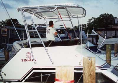Atlantic Towers Top installed on a white Trojan 30 Sport Cruiser boat docked near wooden pilings with a man on board.