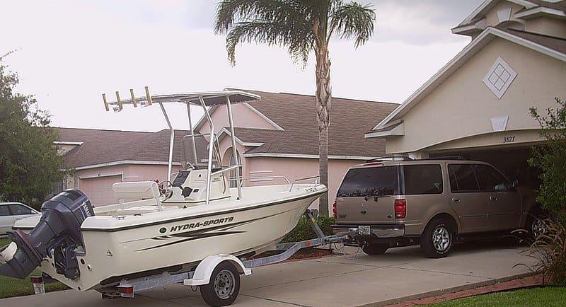 Hydra Sports 180 boat with Atlantic Towers T-Top on a trailer hitched to an SUV in a residential driveway.