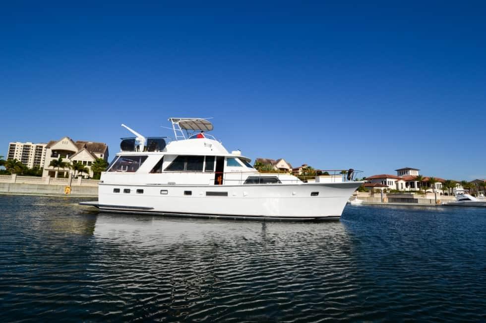 White Hattaras yacht with Atlantic Towers Top installed, cruising in calm waters near waterfront homes under a clear blue sky.