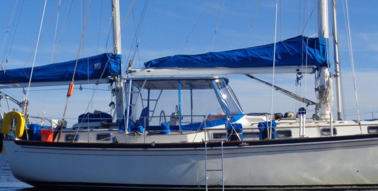 Atlantic Towers Top installed on a Whitby sailboat with a blue canopy, docked in calm waters under a clear sky.