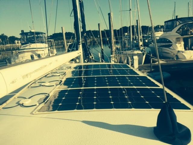 Atlantic Towers Top installed with solar panels on the deck of a sailboat docked at a marina with other boats.
