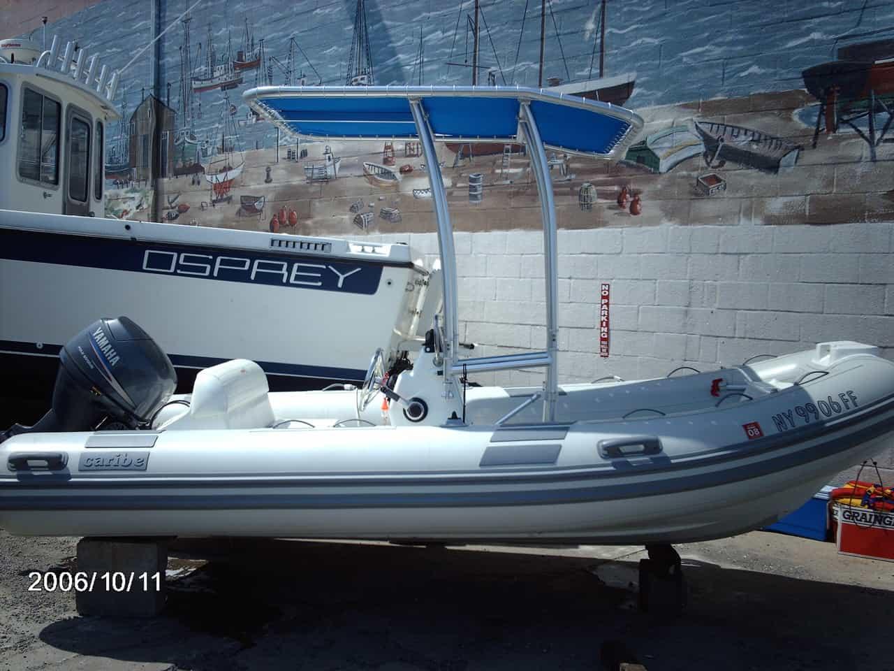 Caribe 15 RIB boat with Atlantic Towers T-Top installed, parked on blocks near a mural and another boat.
