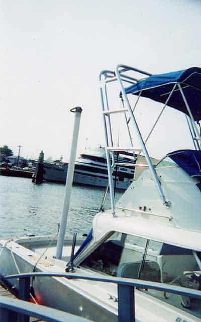 Bertram 25 Flybridge boat docked with Atlantic Towers arch and blue canopy on the flybridge above the cabin.