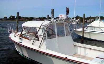 Fortier Boats 26 with installed Atlantic Towers Arch, docked near other boats on calm water near shore.