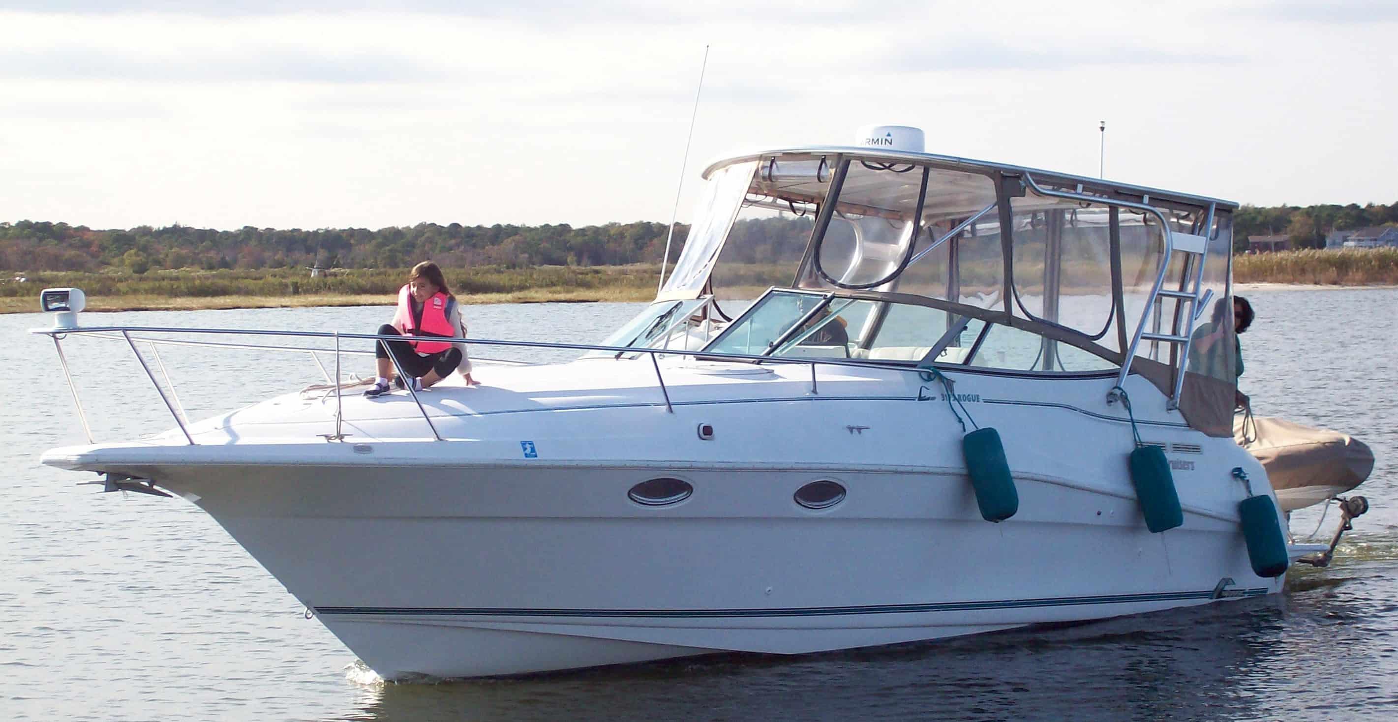 White Cruisers 3175 Rogue boat featuring Atlantic Towers Top with enclosure and a person wearing a pink life vest seated on the bow