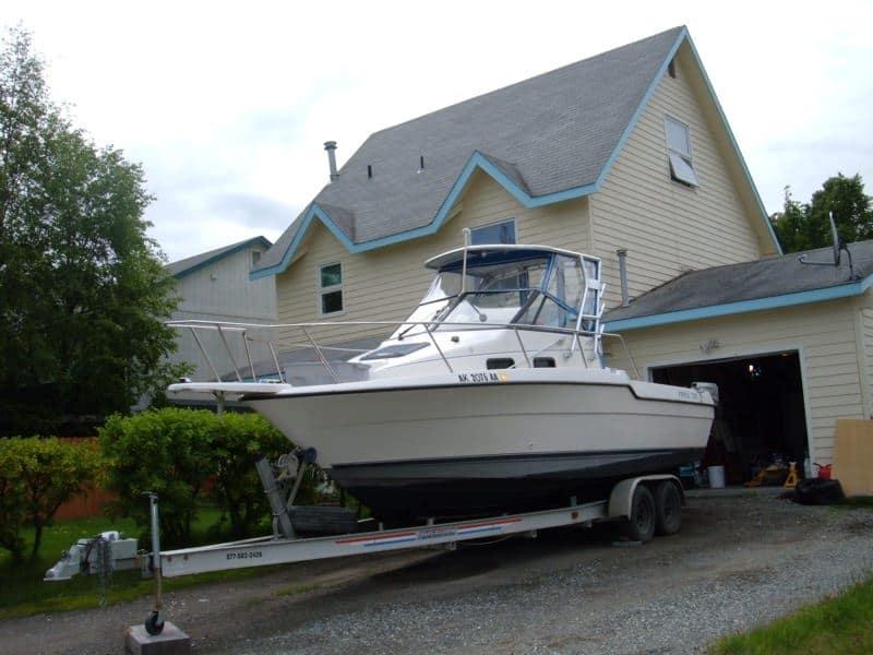 Trophy 2502 Walkaround boat on a trailer with an installed Atlantic Towers Top parked beside a house.