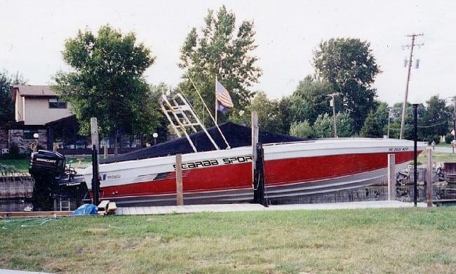 Wellcraft 30 Scarab Sport boat docked with an installed Atlantic Towers Arch and covered interior near trees.