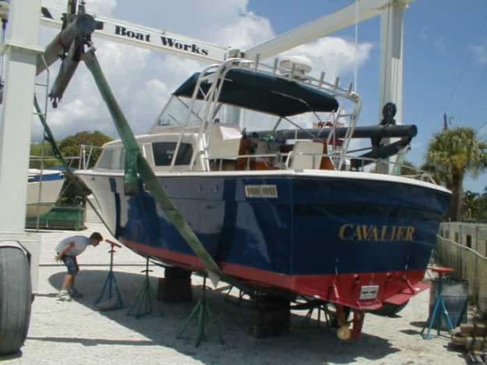Tollycraft Cruiser boat named Cavalier with Atlantic Towers Arch elevated on stands at a marina boatyard.